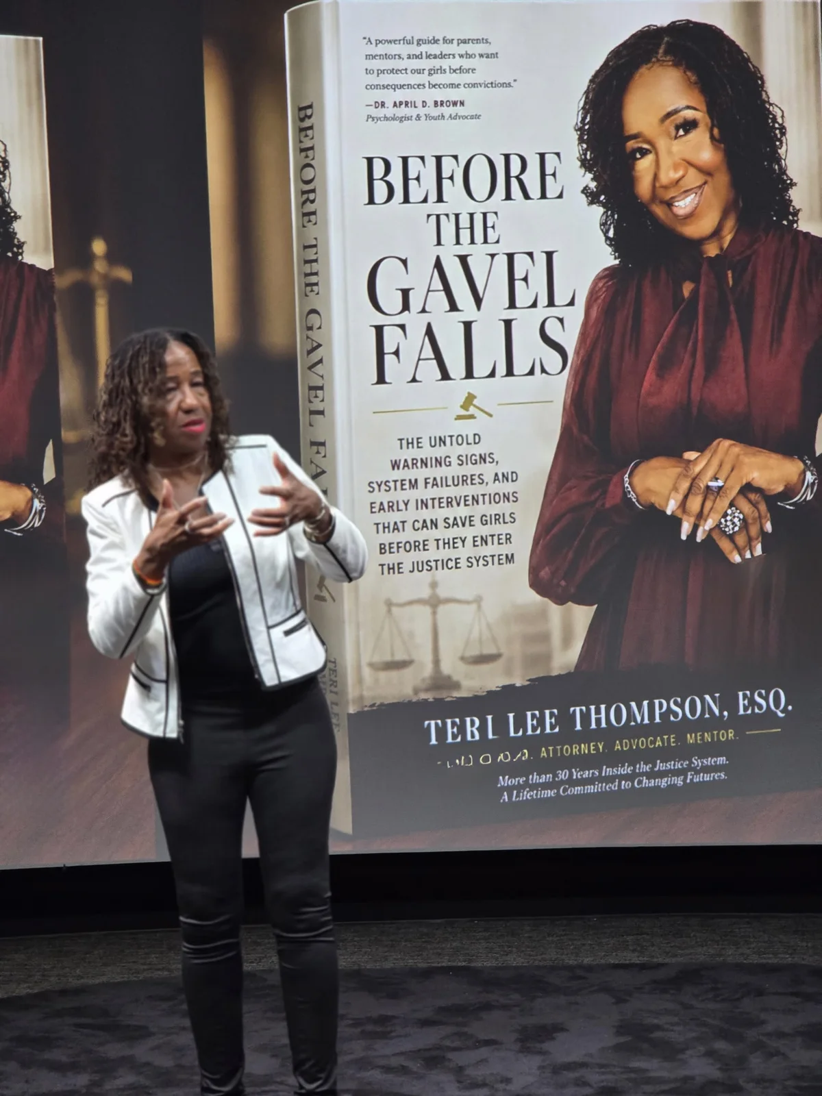 Teri Lee Thompson speaking beside a Before the Gavel Falls display
